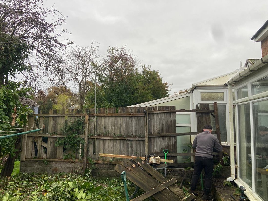 New close-boarded wooden fence across a back garden beside a conservatory, with a washing line and a small table